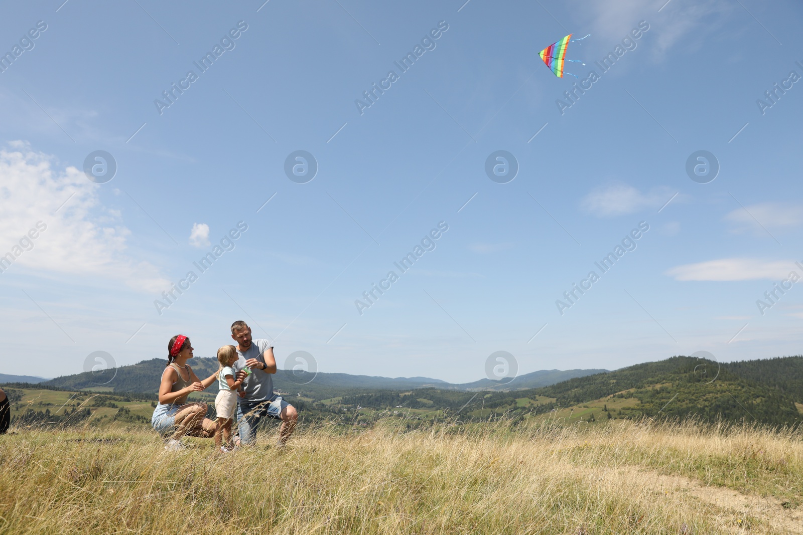 Photo of Family flying kite at field under blue sky