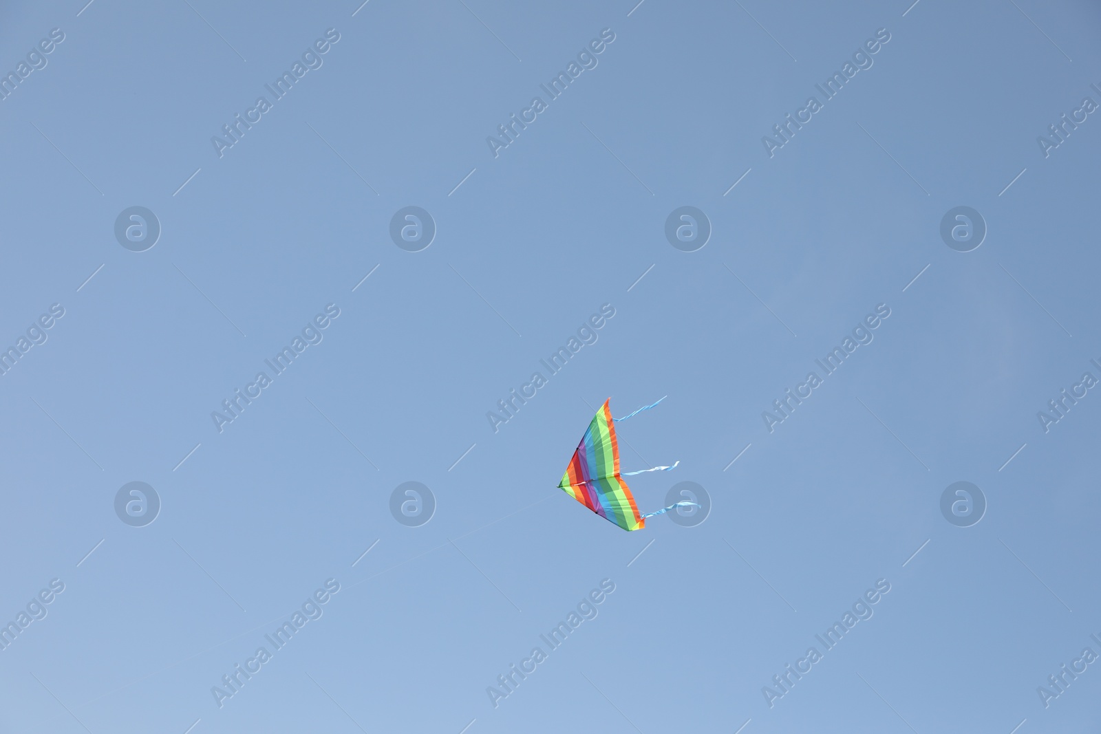 Photo of One colorful kite flying in blue sky. Space for text