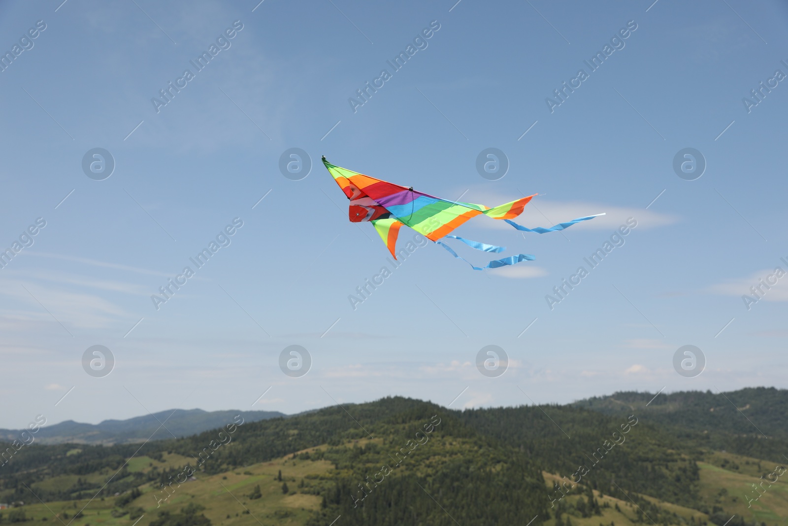 Photo of One colorful kite flying in mountains under blue sky