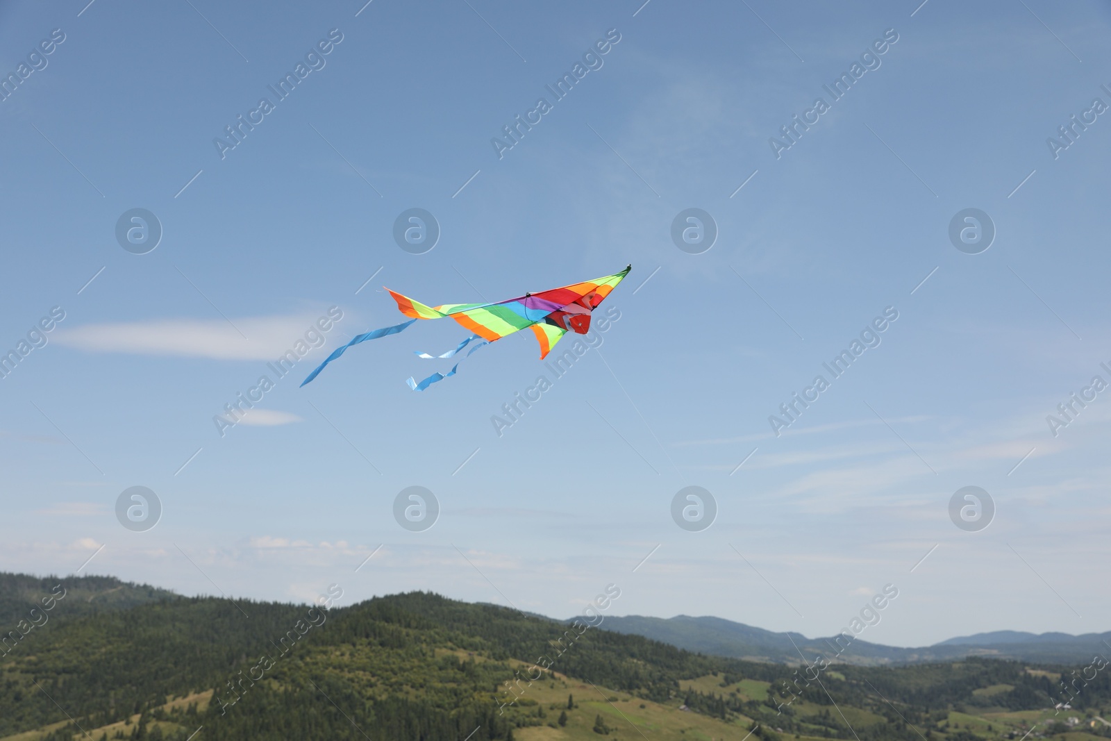 Photo of One colorful kite flying in mountains under blue sky