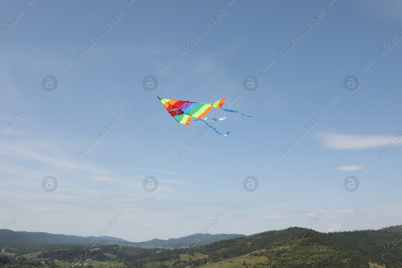 Photo of One colorful kite flying in mountains under blue sky