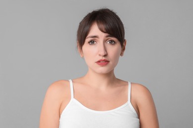 Portrait of frustrated woman on grey background