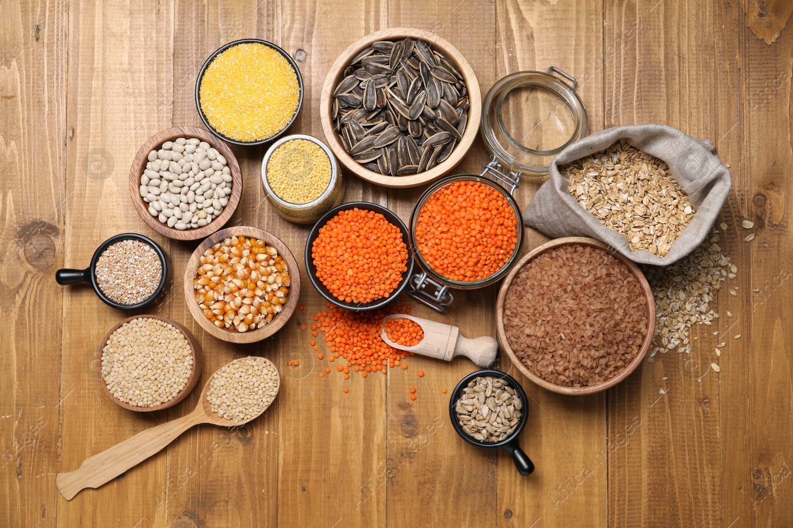 Photo of Different types of cereals, seeds and legumes on wooden table, flat lay