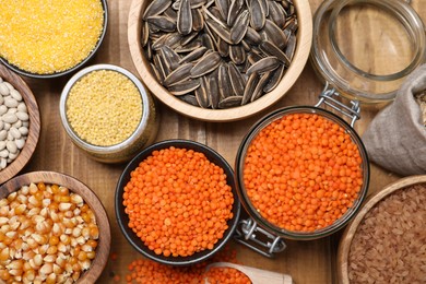 Photo of Different types of cereals, seeds and legumes on wooden table, flat lay