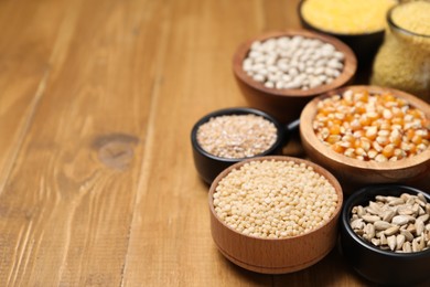 Photo of Different types of cereals, seeds and legumes on wooden table, closeup. Space for text