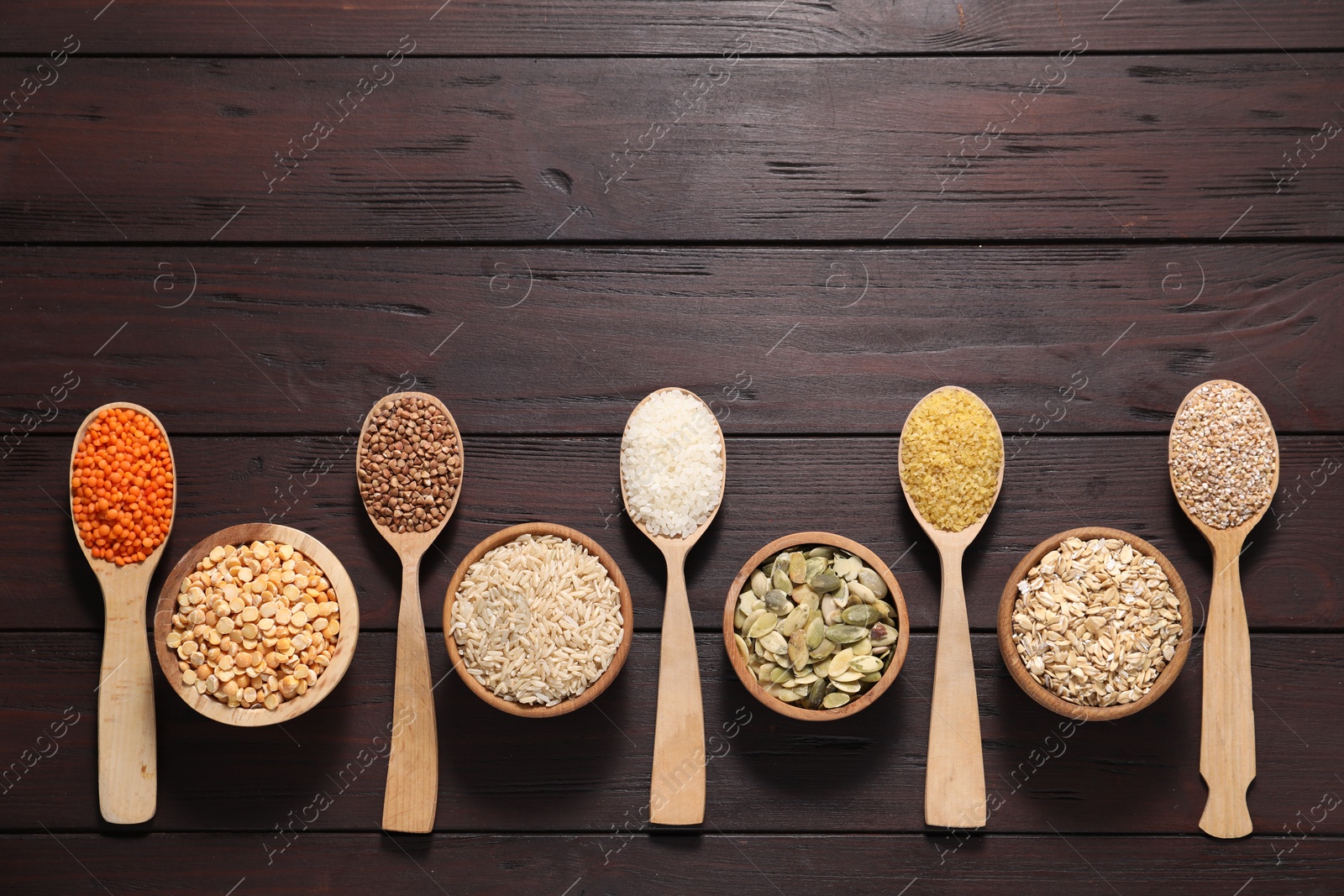 Photo of Different types of cereals, seeds and legumes on wooden table, flat lay. Space for text