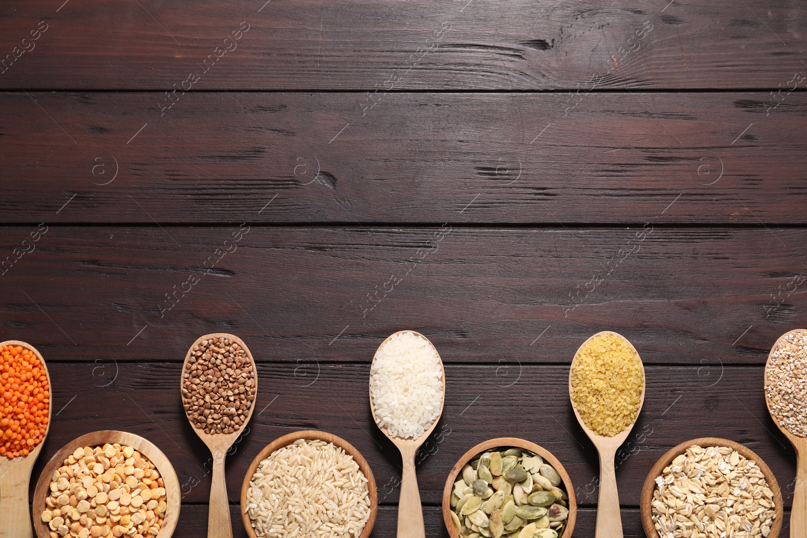 Photo of Different types of cereals, seeds and legumes on wooden table, flat lay. Space for text