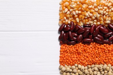 Different types of legumes on white wooden table, flat lay. Space for text