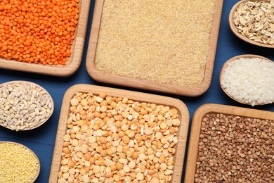 Different types of legumes and cereals on blue wooden table, flat lay