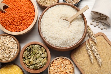 Different types of legumes, cereals and seeds on white wooden table, flat lay