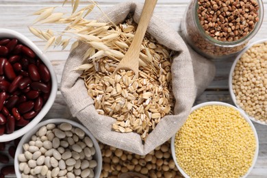 Photo of Different types of legumes and cereals on white wooden table, flat lay