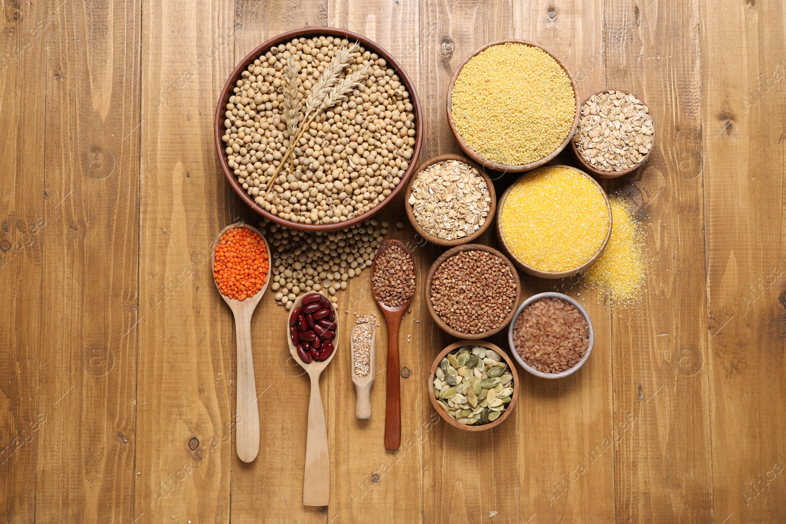 Photo of Different types of legumes, seeds and cereals on wooden table, flat lay