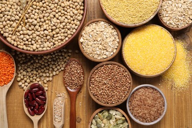 Photo of Different types of legumes, seeds and cereals on wooden table, flat lay