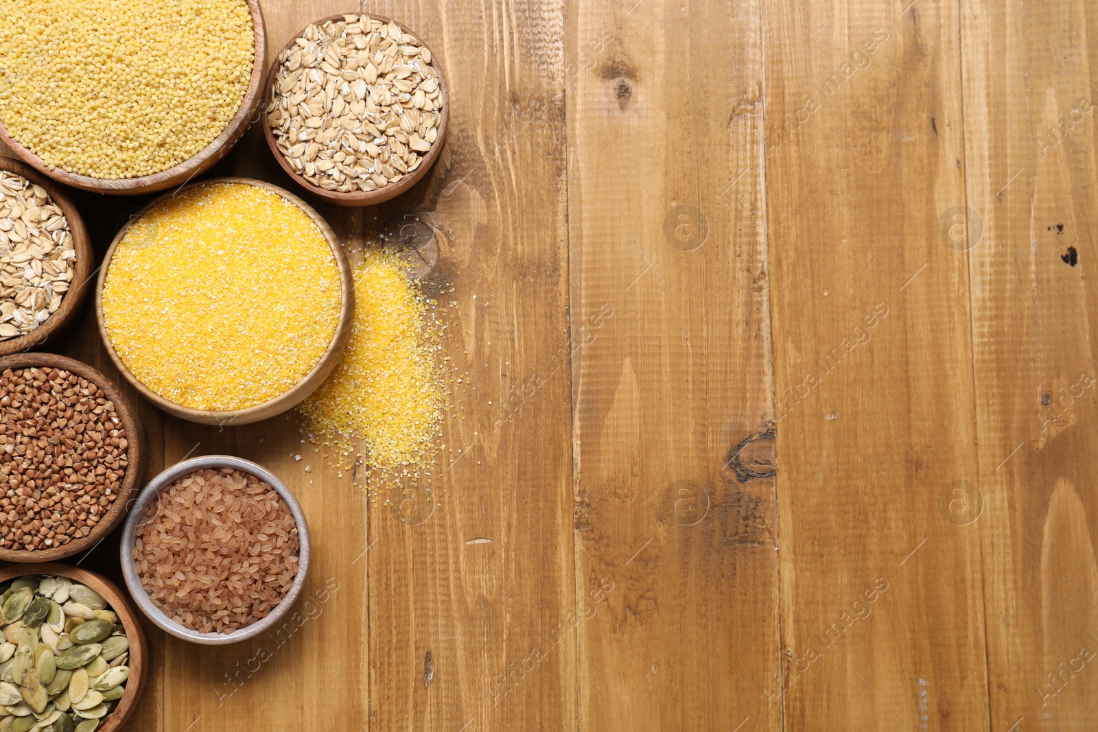 Photo of Different types of seeds and cereals in bowls on wooden table, flat lay. Space for text