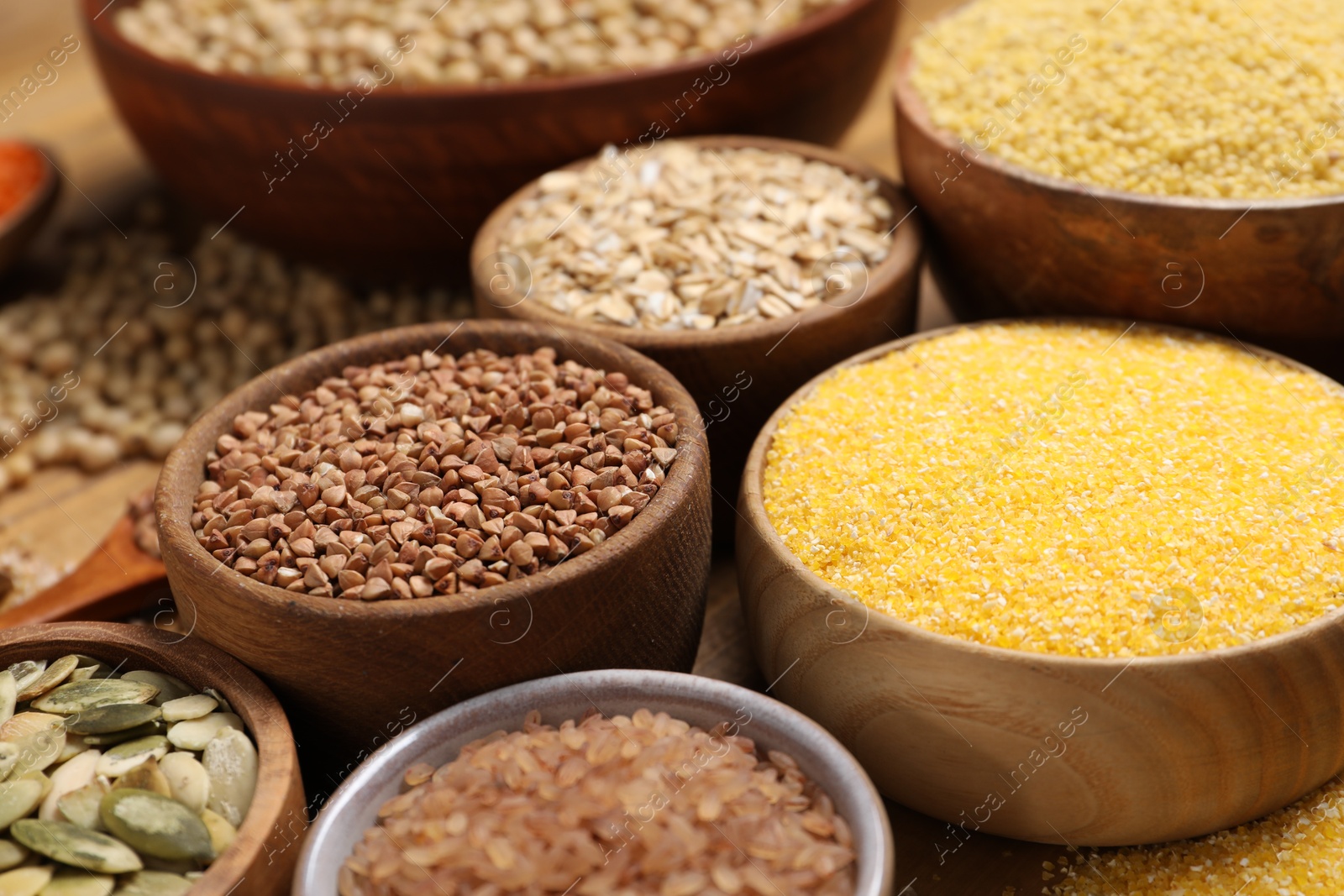 Photo of Different types of seeds and cereals in bowls on table, closeup