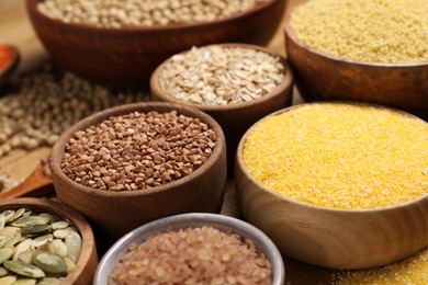 Photo of Different types of seeds and cereals in bowls on table, closeup