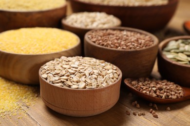 Photo of Different types of cereals and seeds on wooden table, closeup