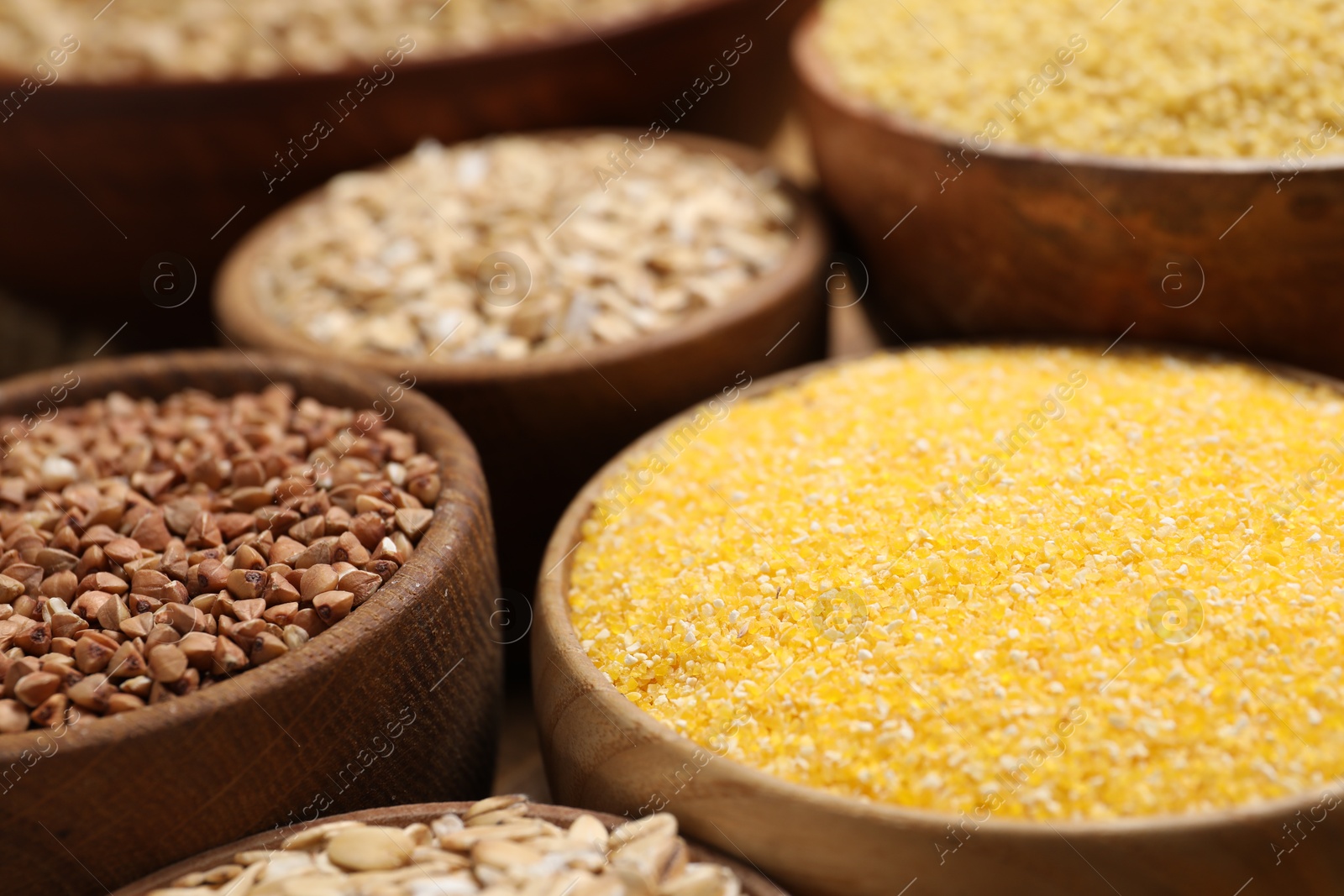 Photo of Different types of cereals in bowls on table, closeup