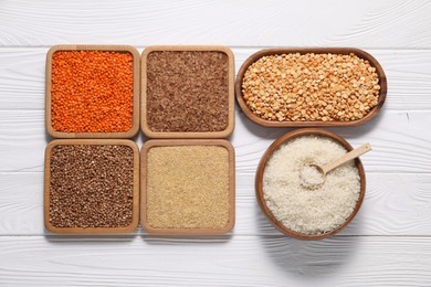 Photo of Different types of cereals and legumes on white wooden table, flat lay