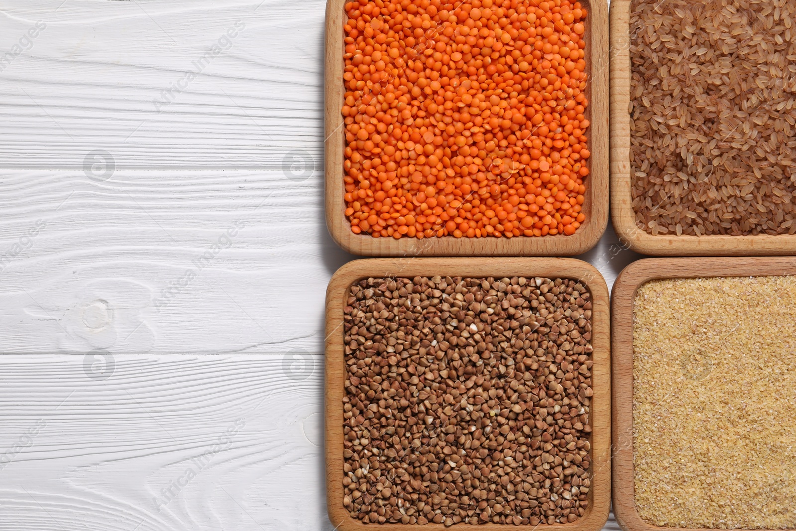 Photo of Different types of cereals and legumes on white wooden table, flat lay. Space for text