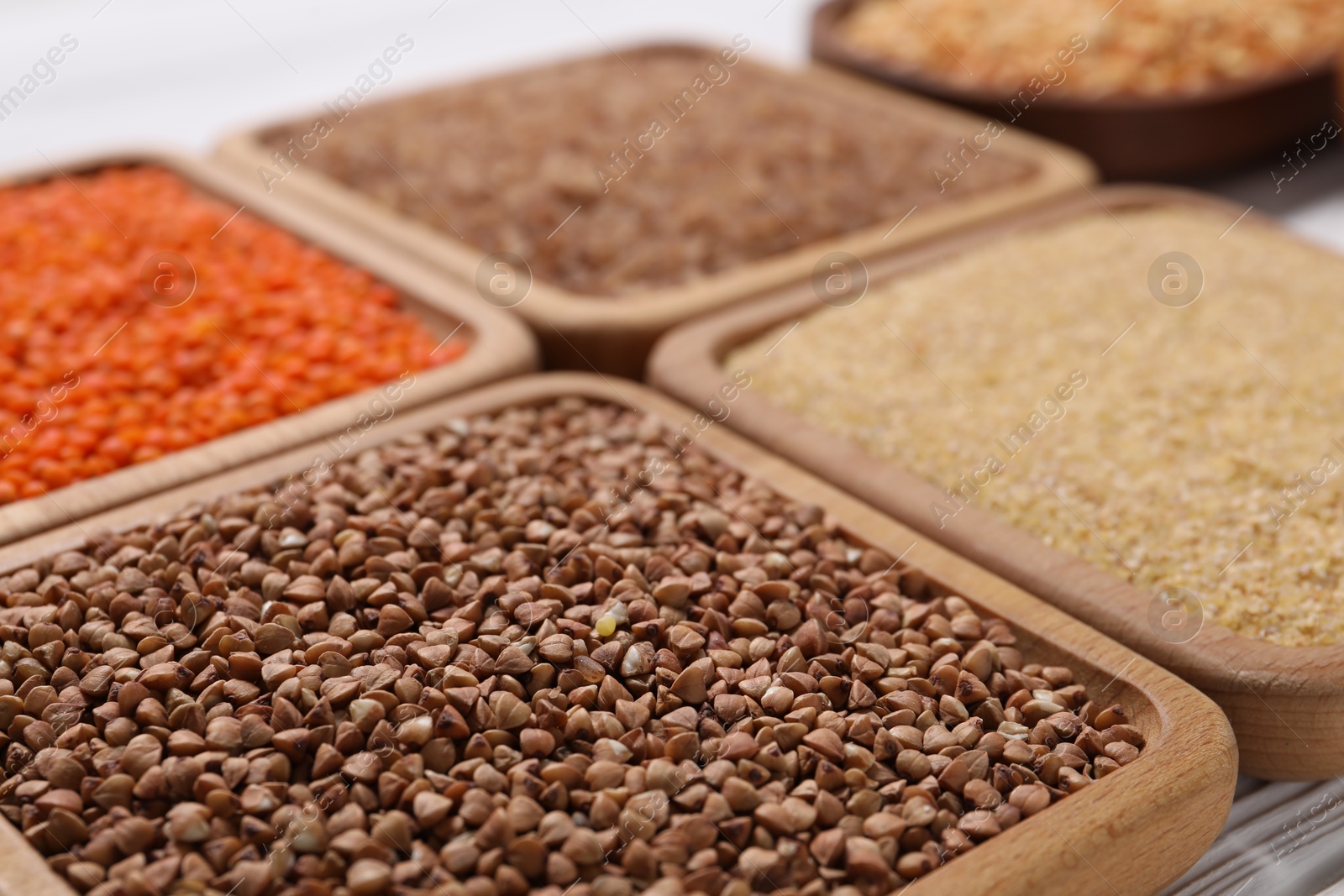 Photo of Different types of cereals and legumes on white table, closeup