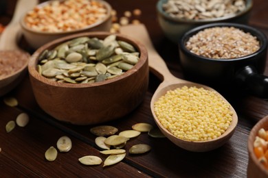 Photo of Different types of seeds and cereals on wooden table, closeup