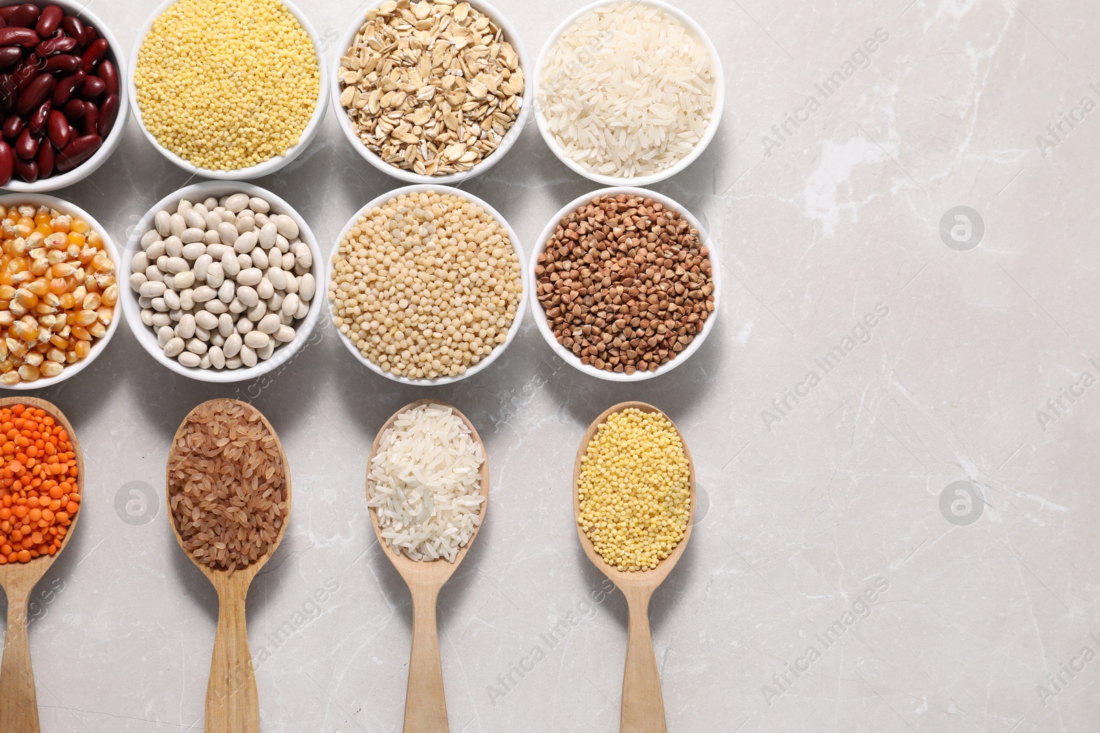 Photo of Different types of legumes and cereals on light marble table, flat lay. Space for text