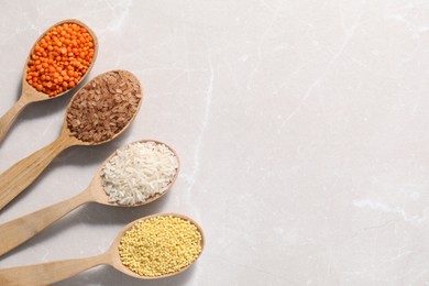 Photo of Different types of legumes and cereals in wooden spoons on light marble table, flat lay. Space for text