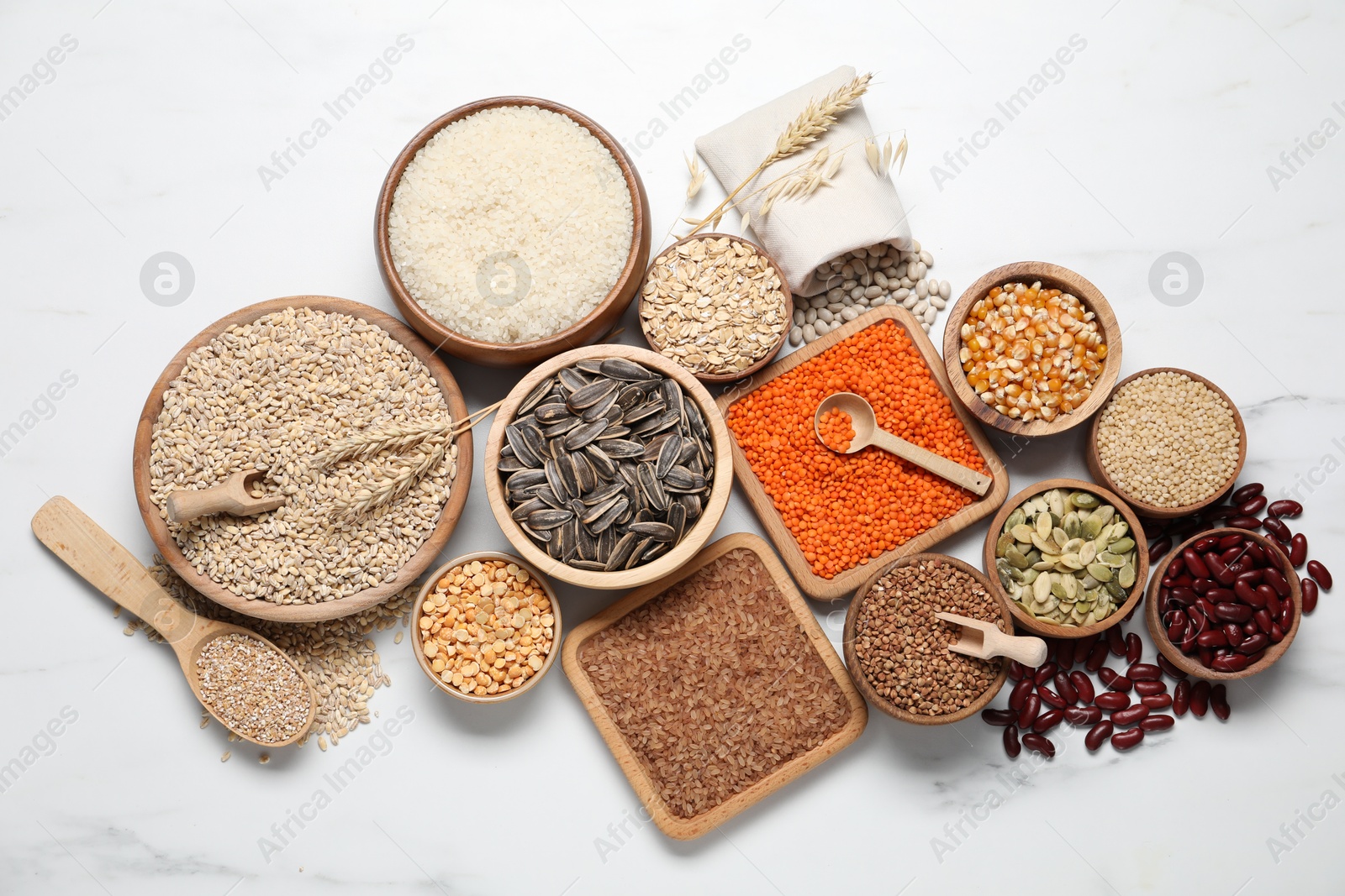 Photo of Different types of legumes, seeds and cereals on white marble table, flat lay