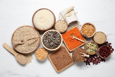 Photo of Different types of legumes, seeds and cereals on white marble table, flat lay