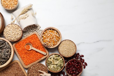 Photo of Different types of legumes, seeds and cereals on white marble table, flat lay. Space for text