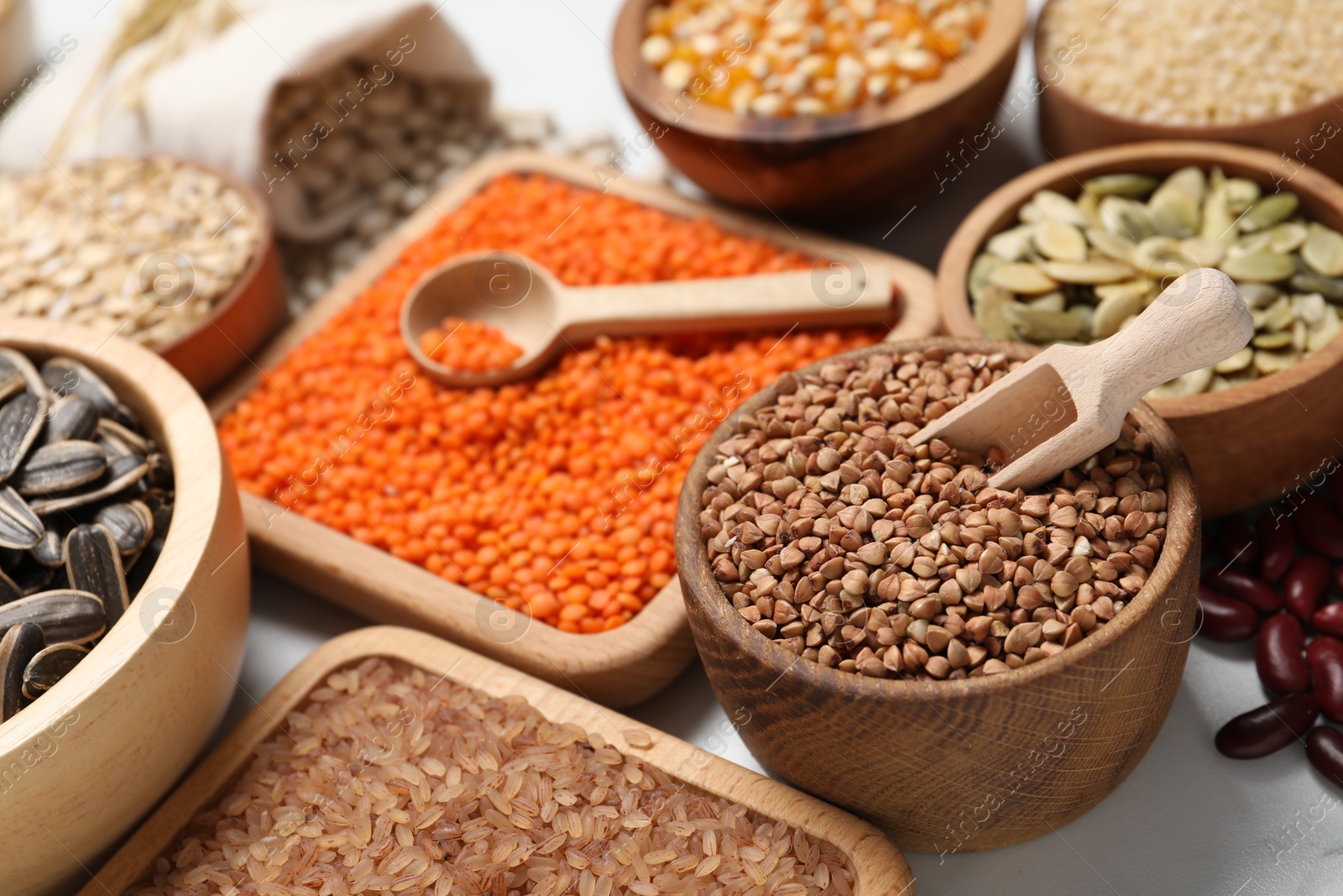 Photo of Different types of seeds, legumes and cereals on white table, closeup