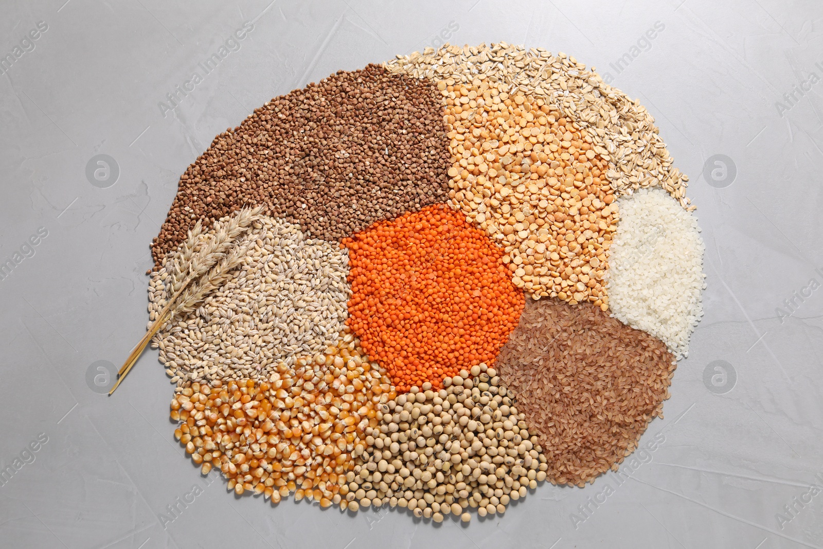 Photo of Different types of legumes and cereals on grey table, top view