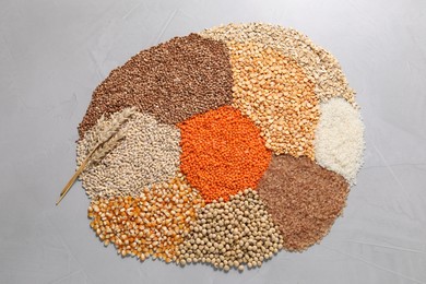 Photo of Different types of legumes and cereals on grey table, top view