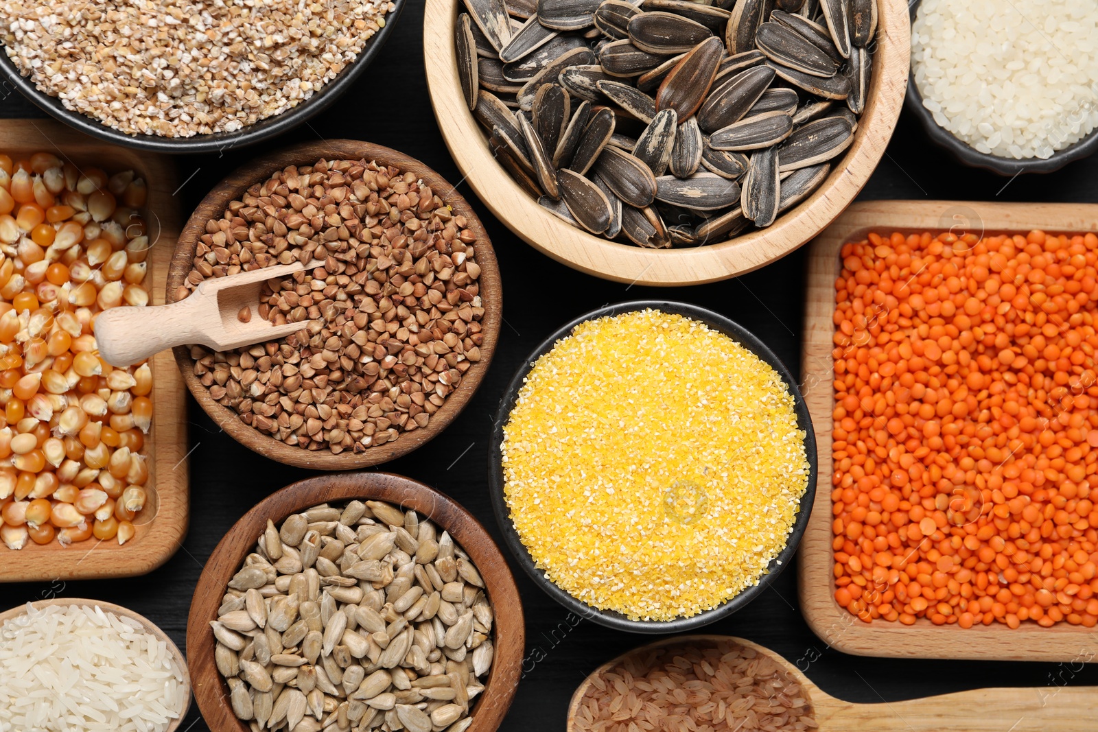 Photo of Different types of legumes, seeds and cereals on black wooden table, flat lay