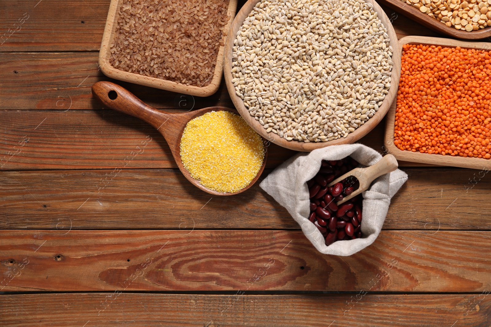 Photo of Different types of cereals and legumes on wooden table, flat lay. Space for text