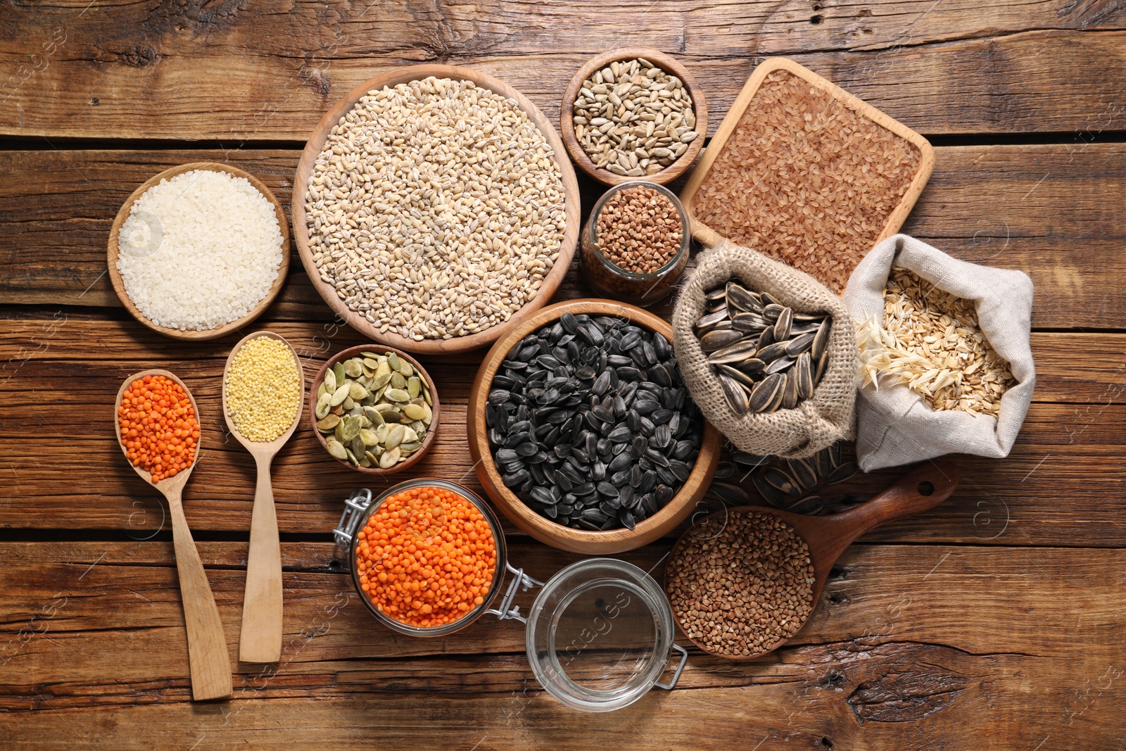 Photo of Different types of cereals, seeds and legumes on wooden table, flat lay