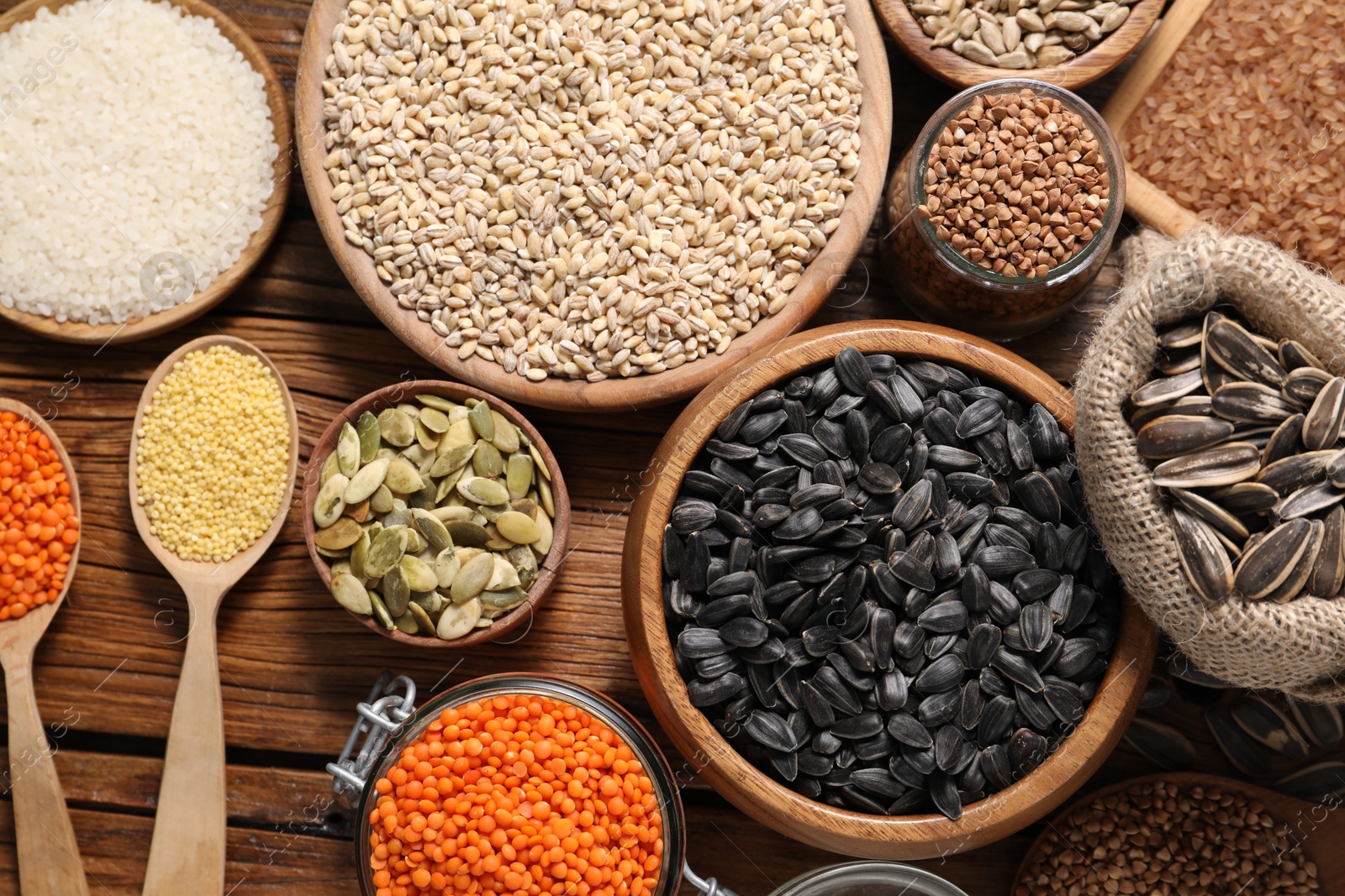 Photo of Different types of cereals, seeds and legumes on wooden table, flat lay