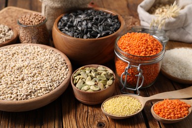 Photo of Different types of cereals, seeds and legumes on wooden table