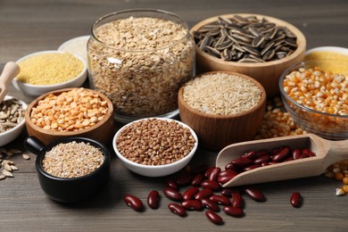 Photo of Different types of cereals, legumes and seeds on wooden table