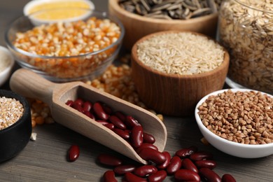 Photo of Different types of cereals, legumes and seeds on wooden table, closeup