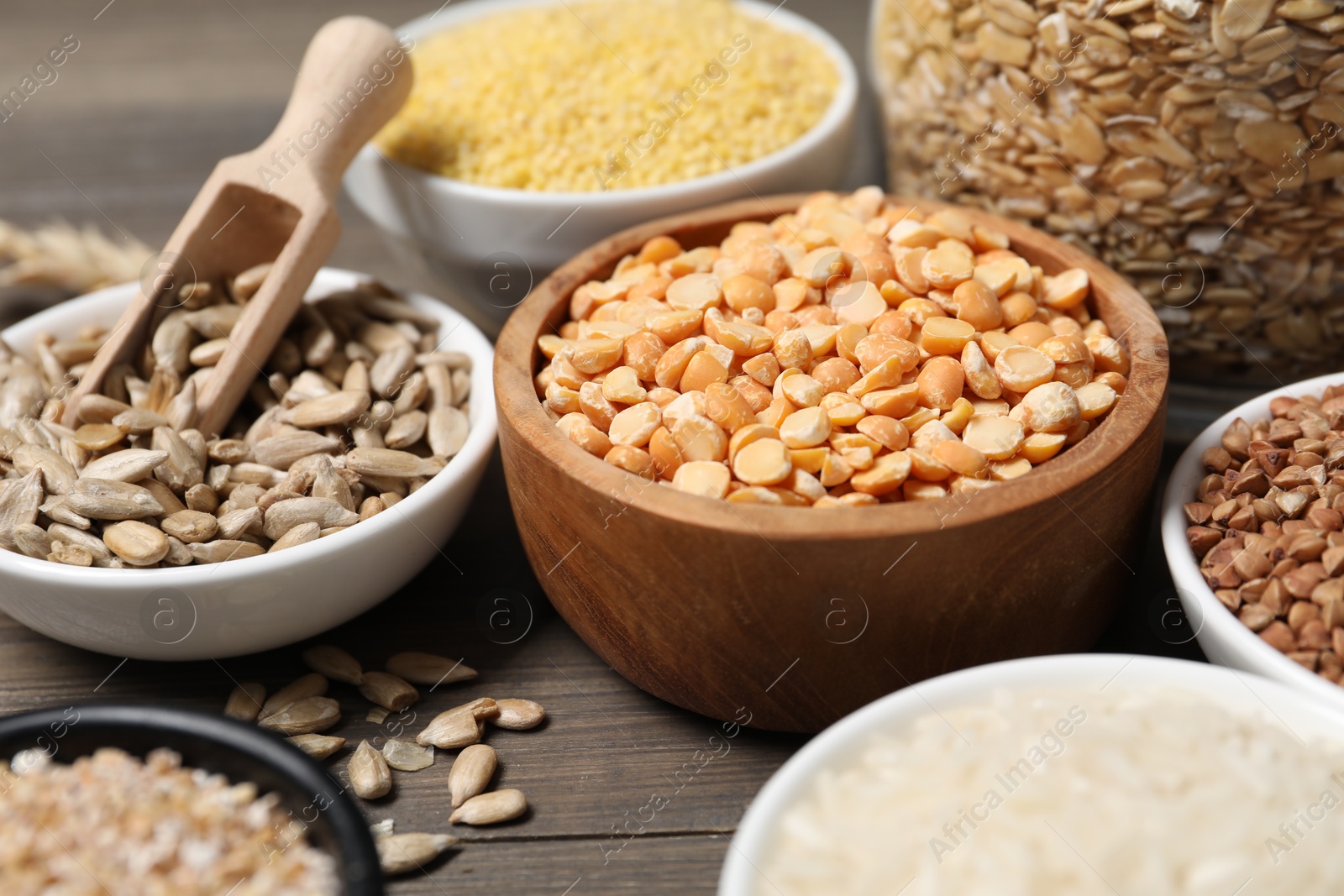 Photo of Different types of cereals and seeds on wooden table, closeup