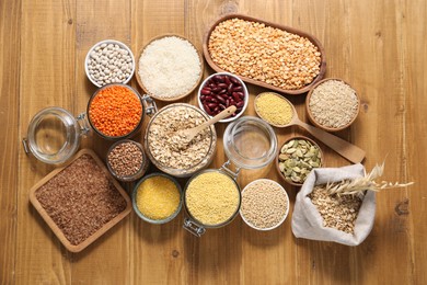 Photo of Different types of cereals, legumes and seeds on wooden table, flat lay