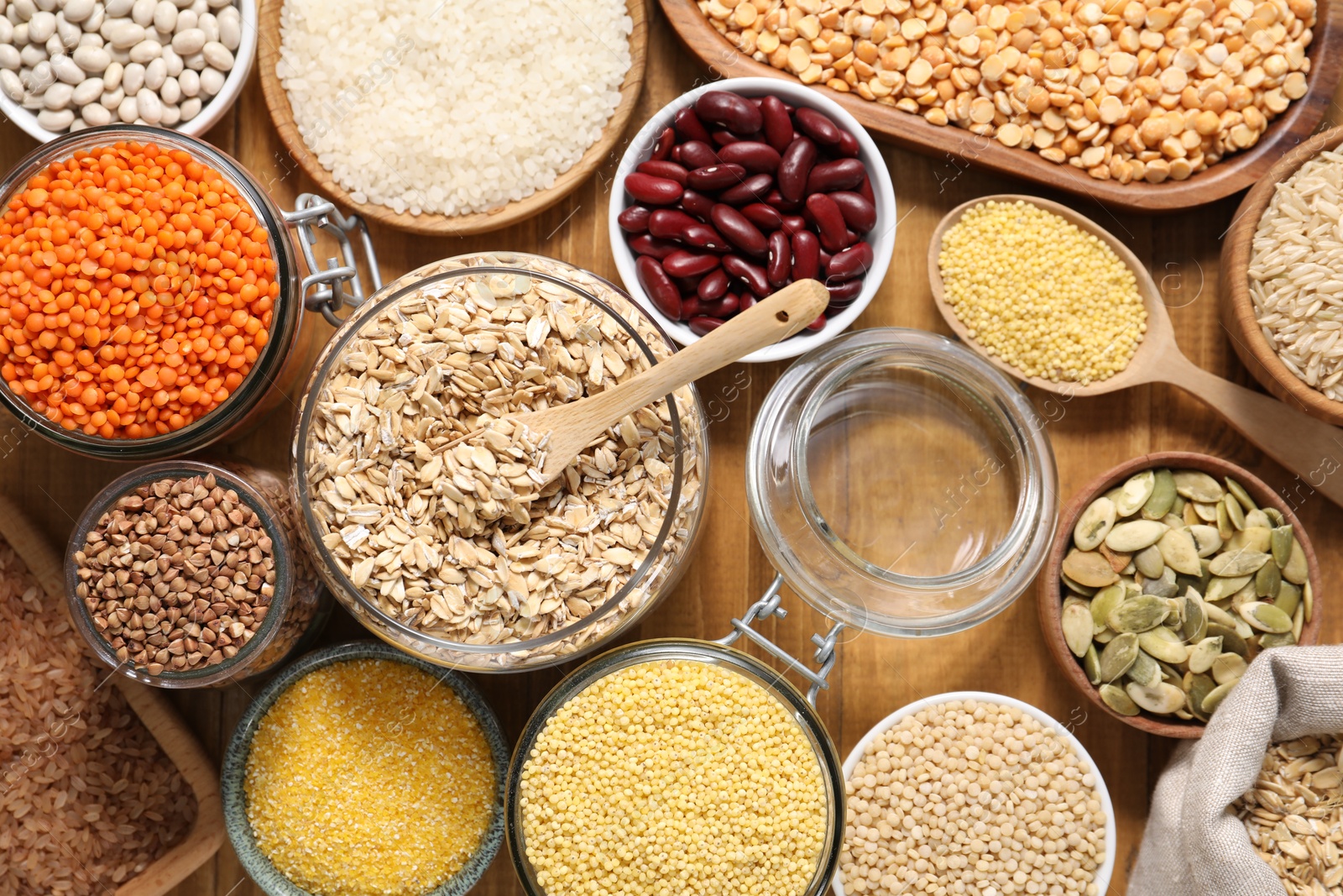 Photo of Different types of cereals, legumes and seeds on wooden table, flat lay