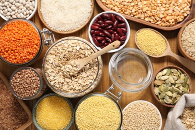 Photo of Different types of cereals, legumes and seeds on wooden table, flat lay