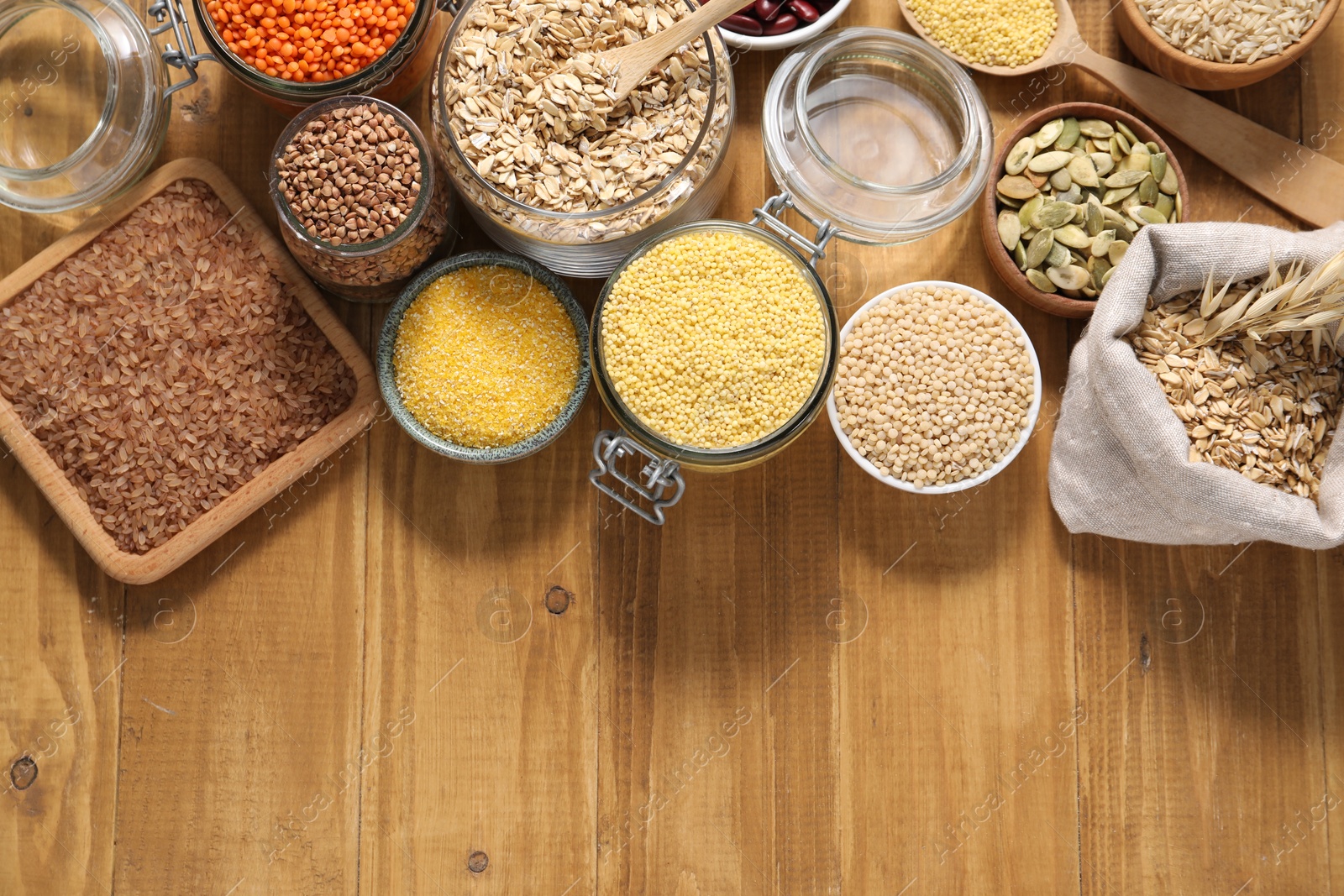 Photo of Different types of cereals, legumes and seeds on wooden table, flat lay. Space for text