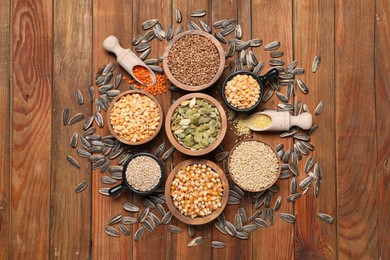 Photo of Different types of cereals, legumes and seeds on wooden table, flat lay