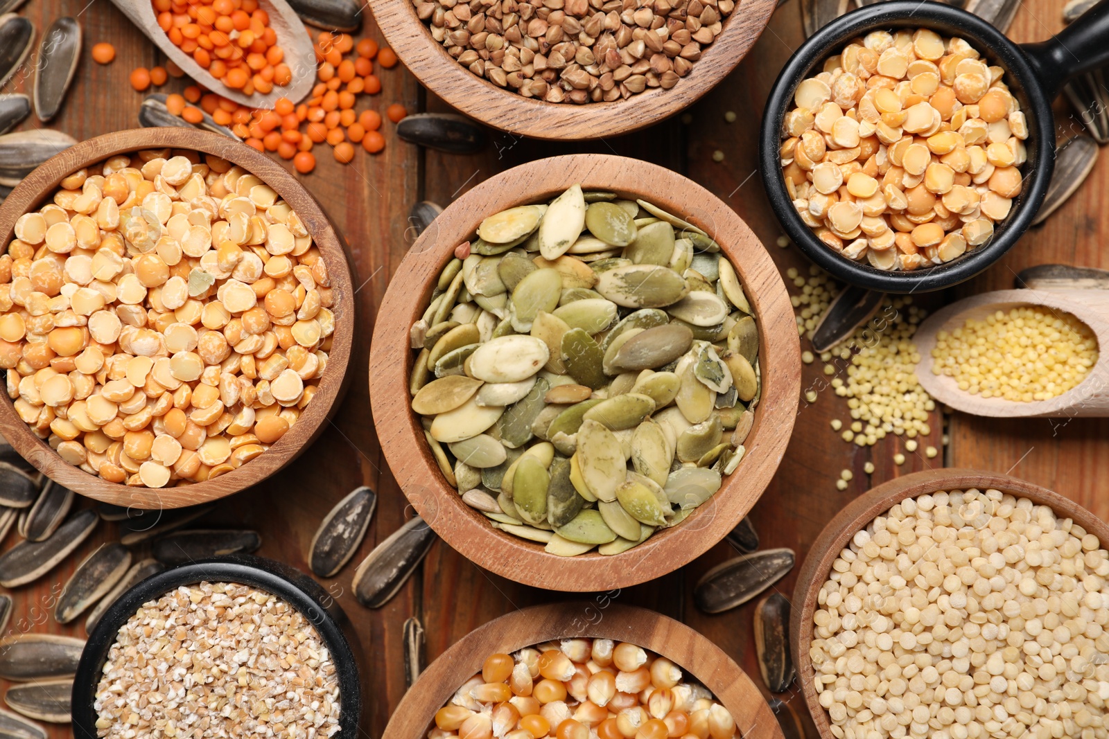 Photo of Different types of cereals, legumes and seeds on wooden table, flat lay