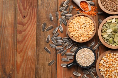 Photo of Different types of cereals, legumes and seeds on wooden table, flat lay. Space for text