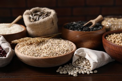 Photo of Different types of cereals, seeds and legumes on wooden table